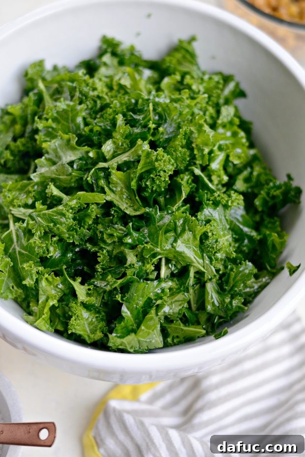 Chopped kale leaves in a large bowl, freshly drizzled with olive oil and sprinkled with kosher salt, ready for massaging.