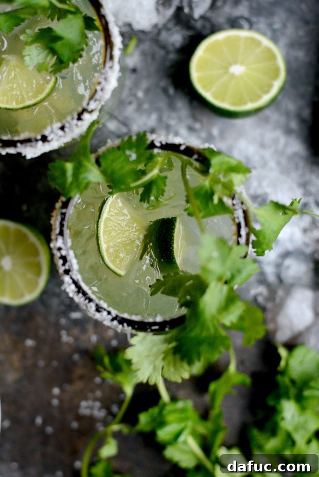 Zesty Cilantro Lime Margaritas 11 Pouring cilantro lime margarita mixture into glasses with ice and tequila