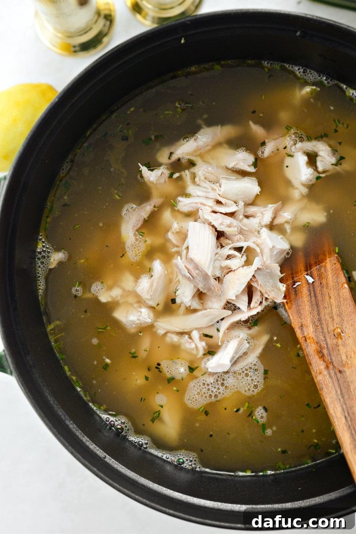 Bright Lemon Rosemary Chicken Noodle Soup 11 Adding shredded cooked chicken to the simmering broth