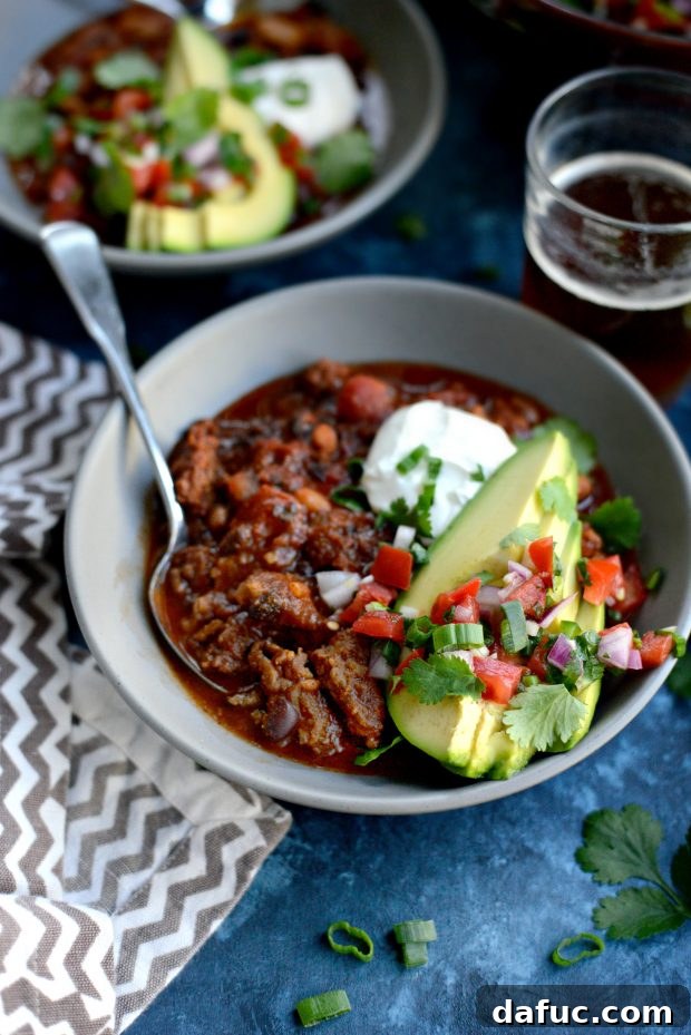 Close-up shot of the rich, deep color of Ancho Chorizo Chili cooking in a pot, highlighting its inviting texture.