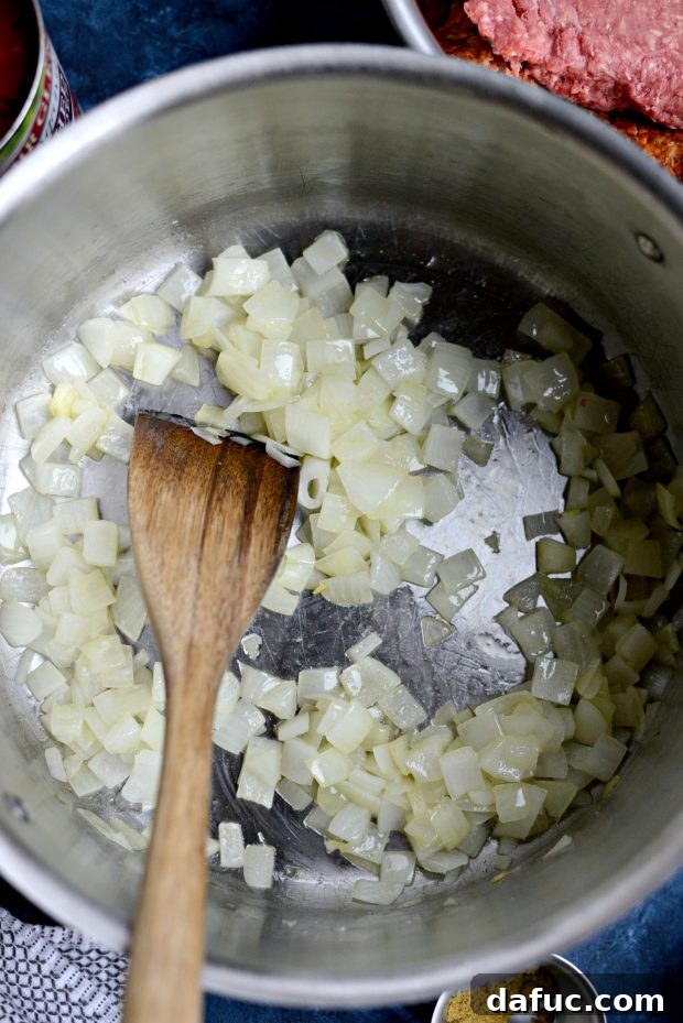Detailed shot of diced yellow onion being sautéed in olive oil, the first step in making Ancho Chorizo Chili.