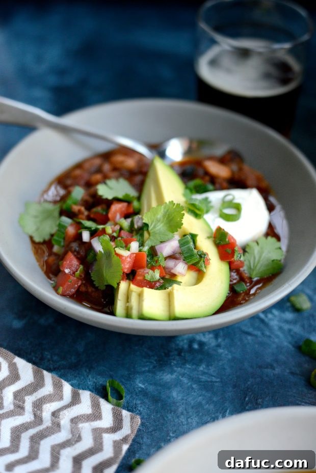 A beautifully garnished bowl of Ancho Chorizo Chili with sour cream, avocado, and pico de gallo.