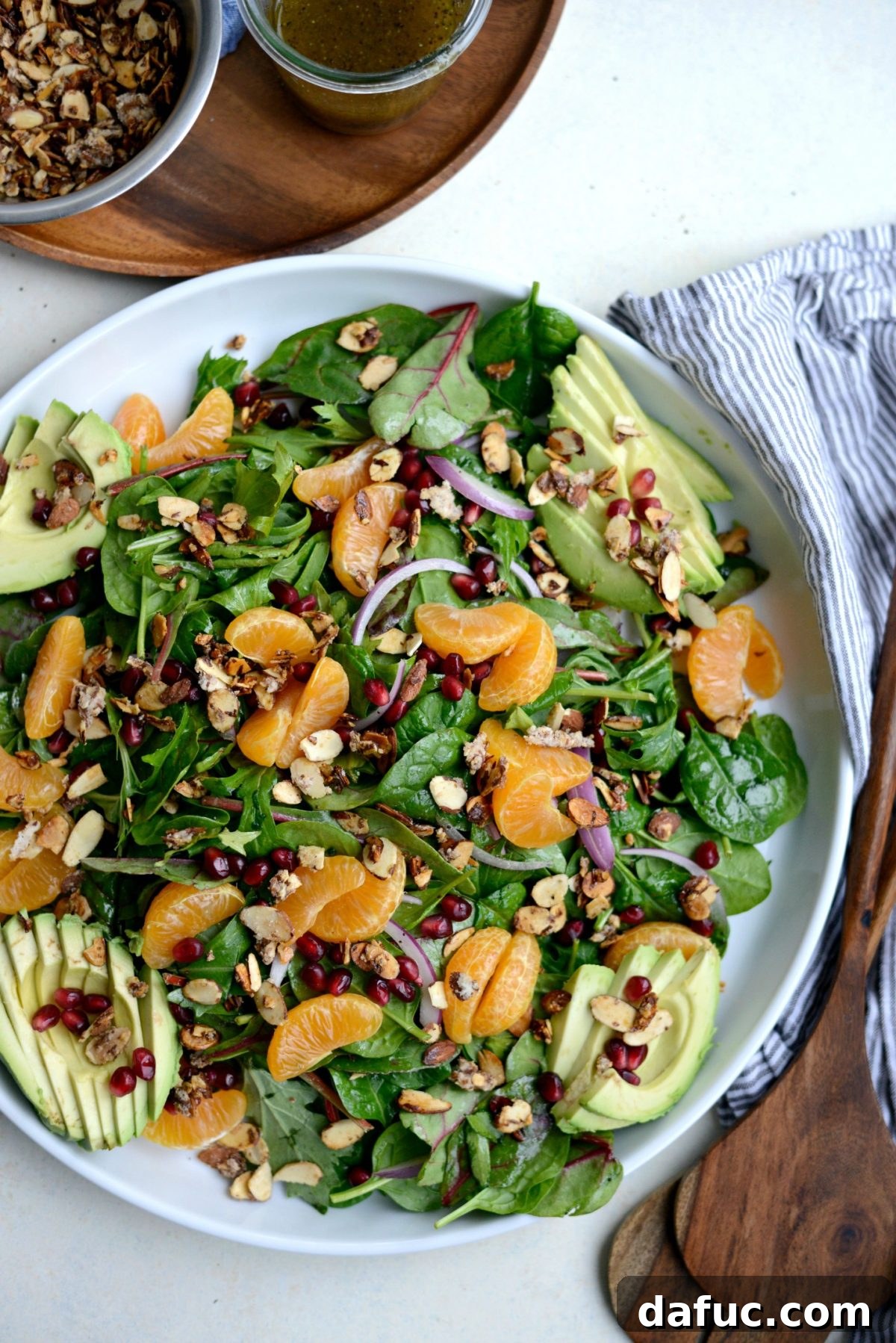 Golden Citrus Poppy Seed Salad 13 top with mandarin segments, sliced avocado, almonds and pomegranate arils.