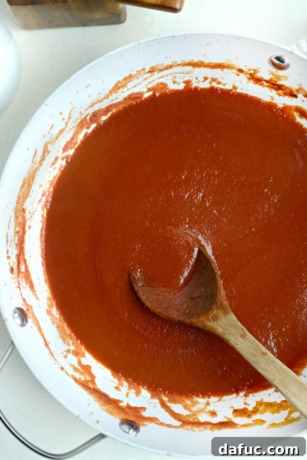 Stirring enchilada sauce to combine and simmer