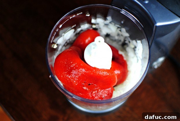 Roasted red peppers being added to the food processor