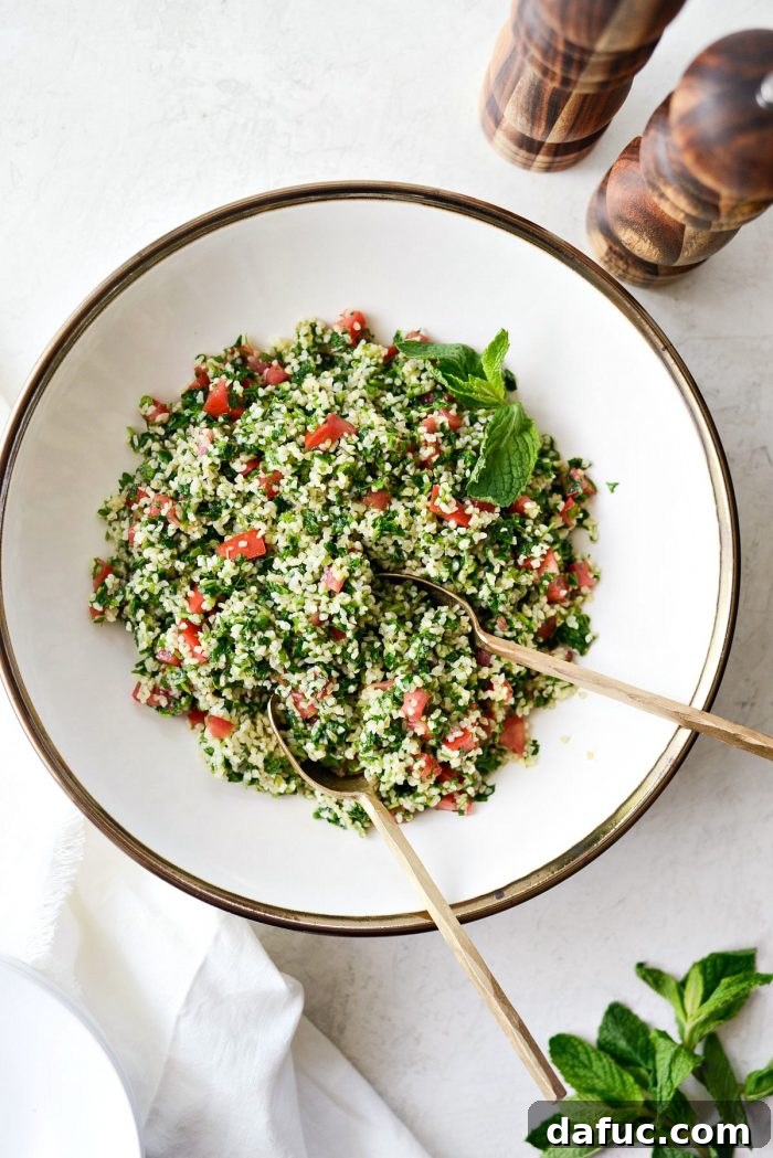 Perfect Homemade Tabbouleh 13 A large bowl of finished homemade tabbouleh, garnished with fresh parsley sprigs and lemon wedges, ready to be served.