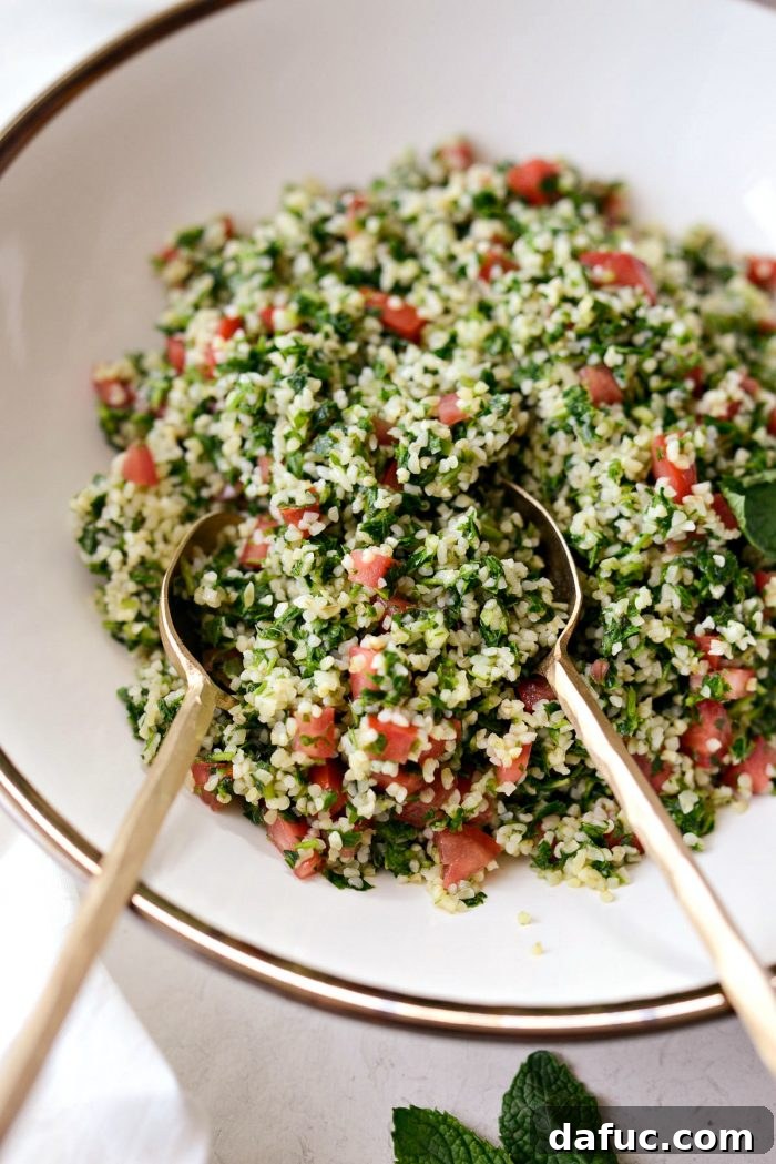 Perfect Homemade Tabbouleh 3 Two elegant gold spoons poised to serve a portion of fresh homemade tabbouleh from a cream bowl with a delicate gold rim, ready to be enjoyed.