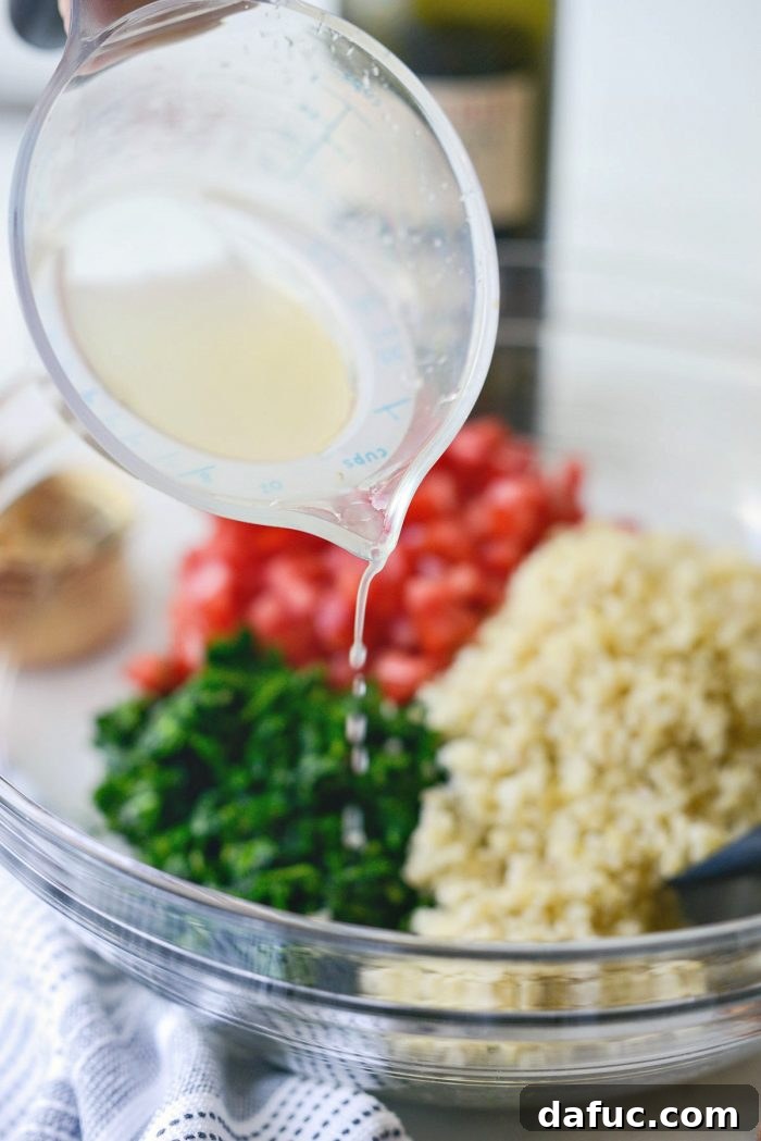 Perfect Homemade Tabbouleh 9 A stream of fresh lemon juice being poured into a mixing bowl containing the finely chopped herbs, bulgur, and tomatoes.