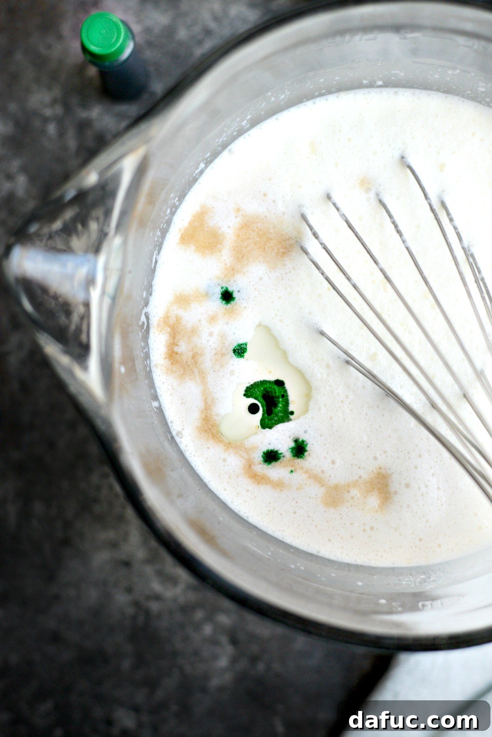 Adding vanilla, peppermint extract, and food coloring to the cream mixture