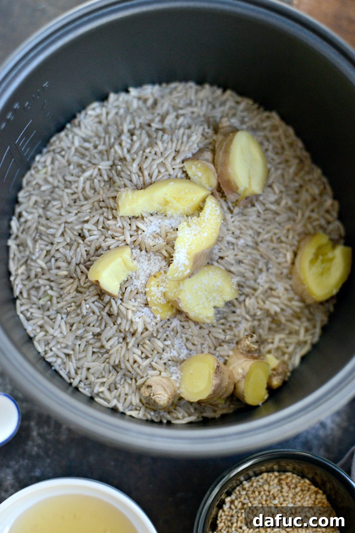 Toasted Sesame Ginger Brown Rice 5 Adding brown rice, sliced ginger, and salt to a rice cooker pot