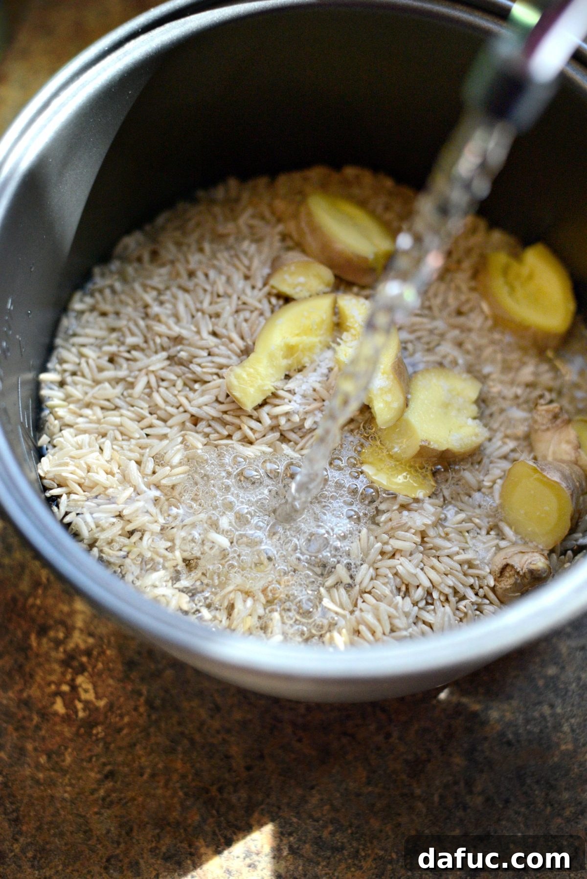 Toasted Sesame Ginger Brown Rice 6 Adding water to the rice cooker pot with rice, ginger, and salt