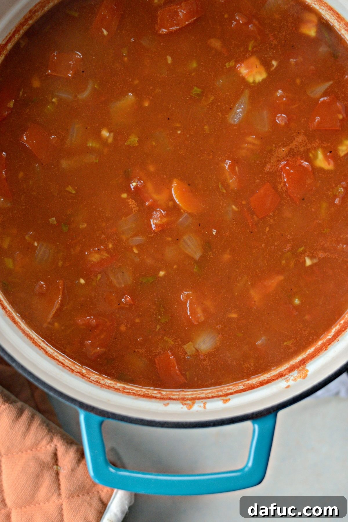 Velvety Tomato Spinach Soup 8 Vegetable broth and crushed tomatoes simmering in a large pot, creating the base for the Florentine soup.