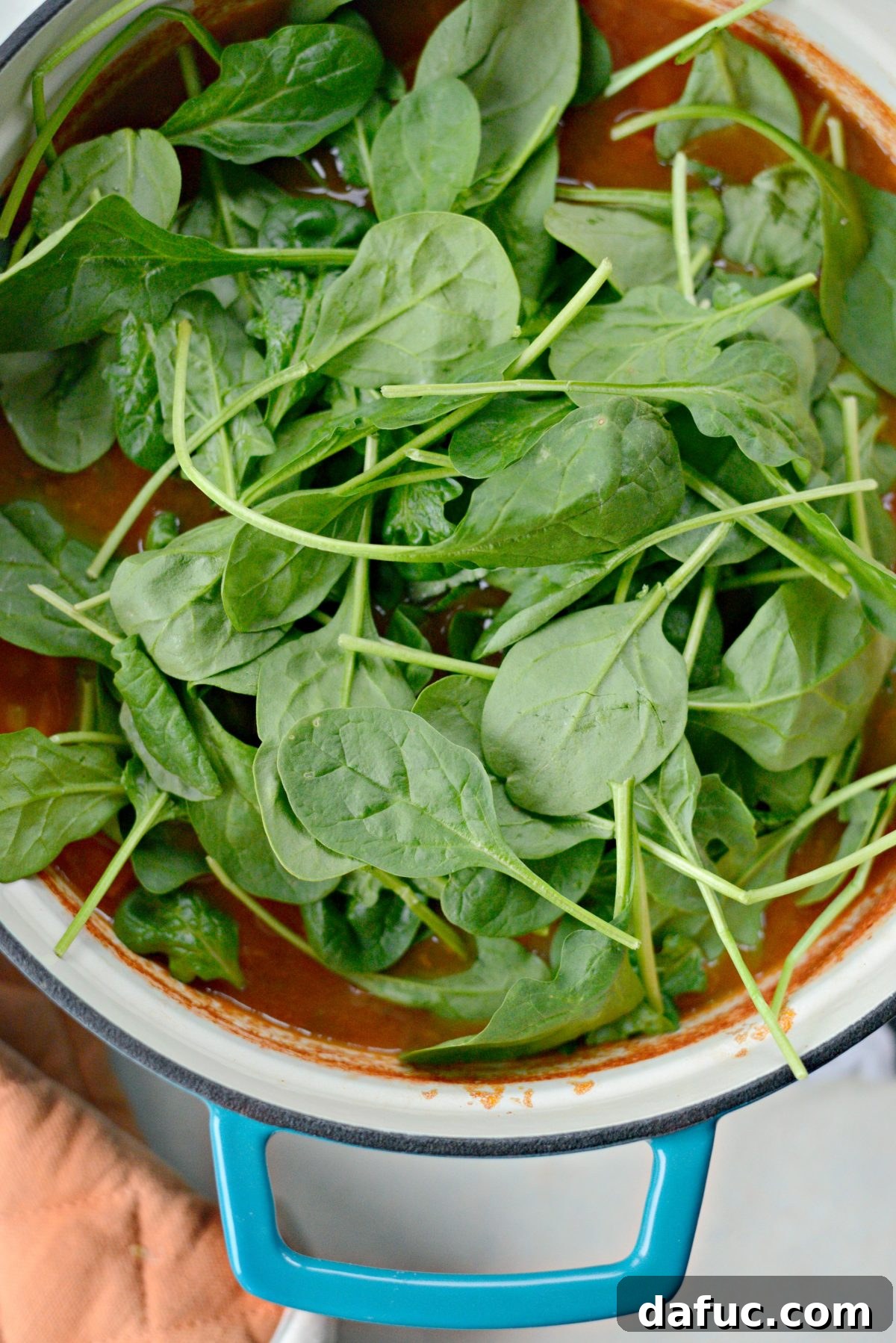 Velvety Tomato Spinach Soup 9 Baby spinach being stirred into the hot Tomato Florentine Soup, wilting quickly.