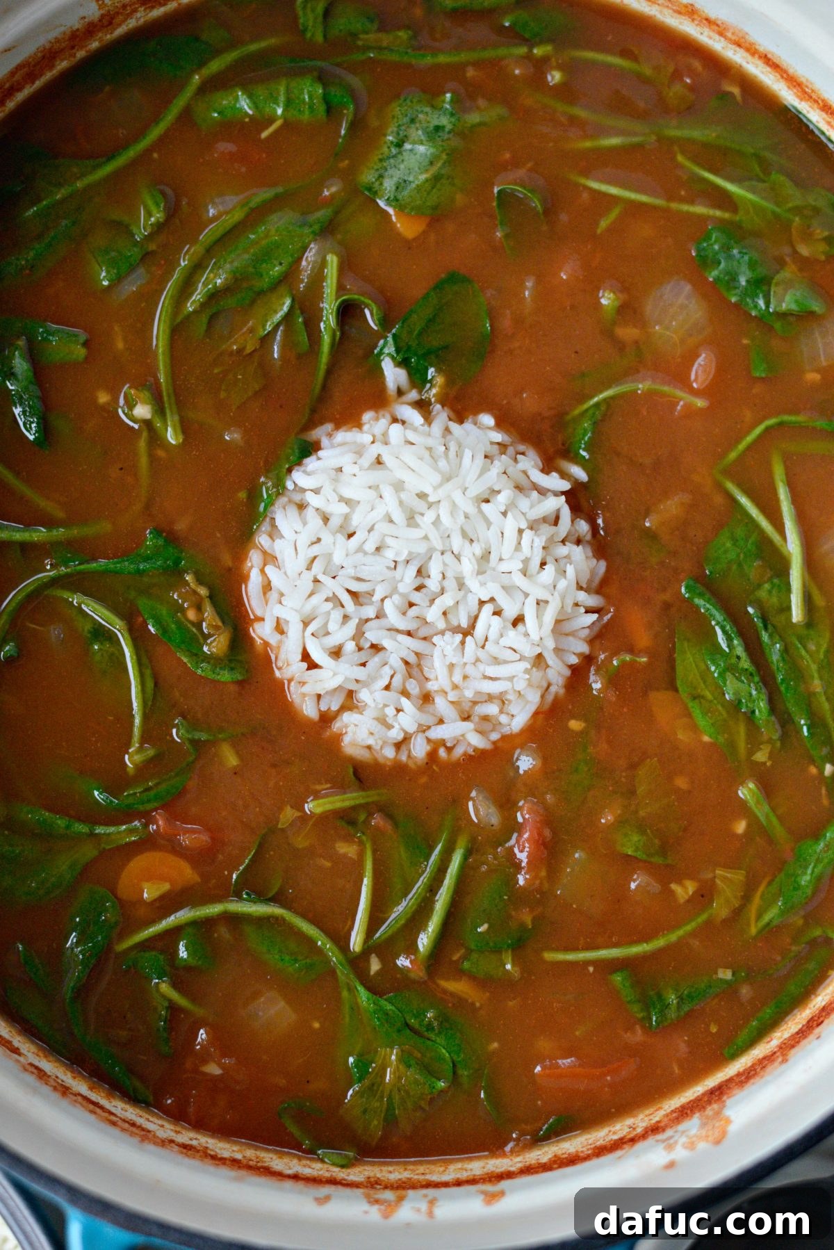 Velvety Tomato Spinach Soup 10 Cooked long grain white rice being stirred into the Tomato Florentine Soup, adding body and texture.
