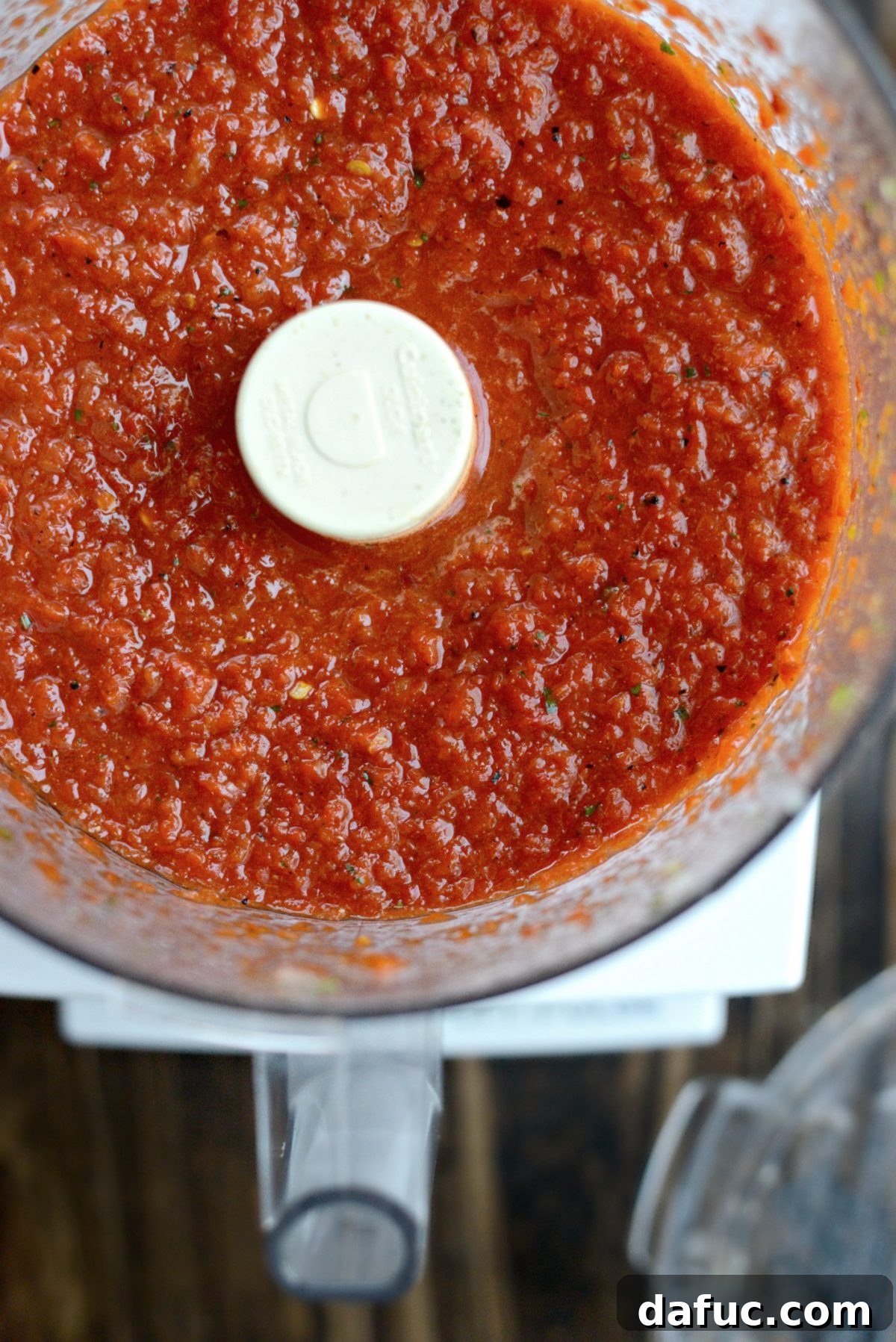 Roasted red pepper harissa being processed until smooth in a food processor.