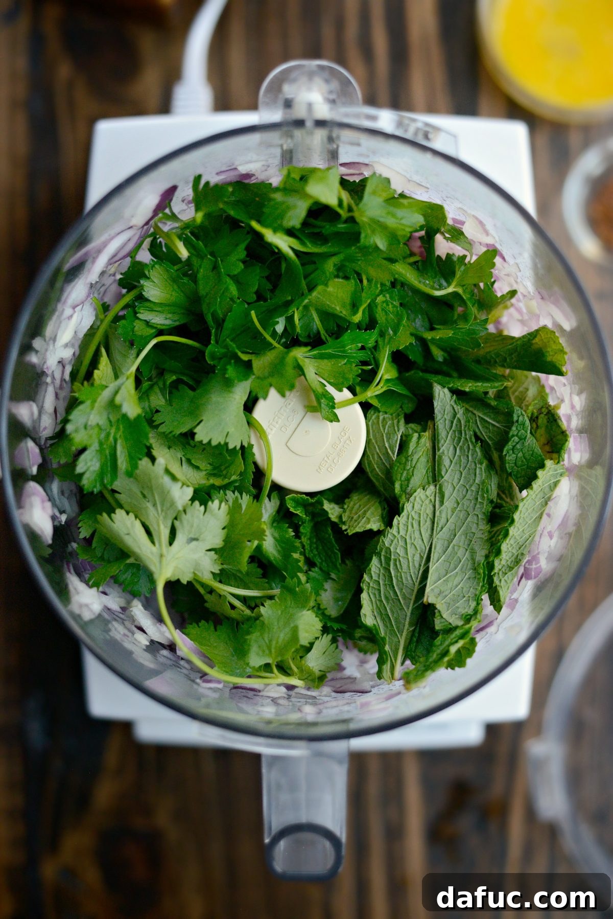 Fresh cilantro, mint, and parsley added to the food processor with onion and garlic.