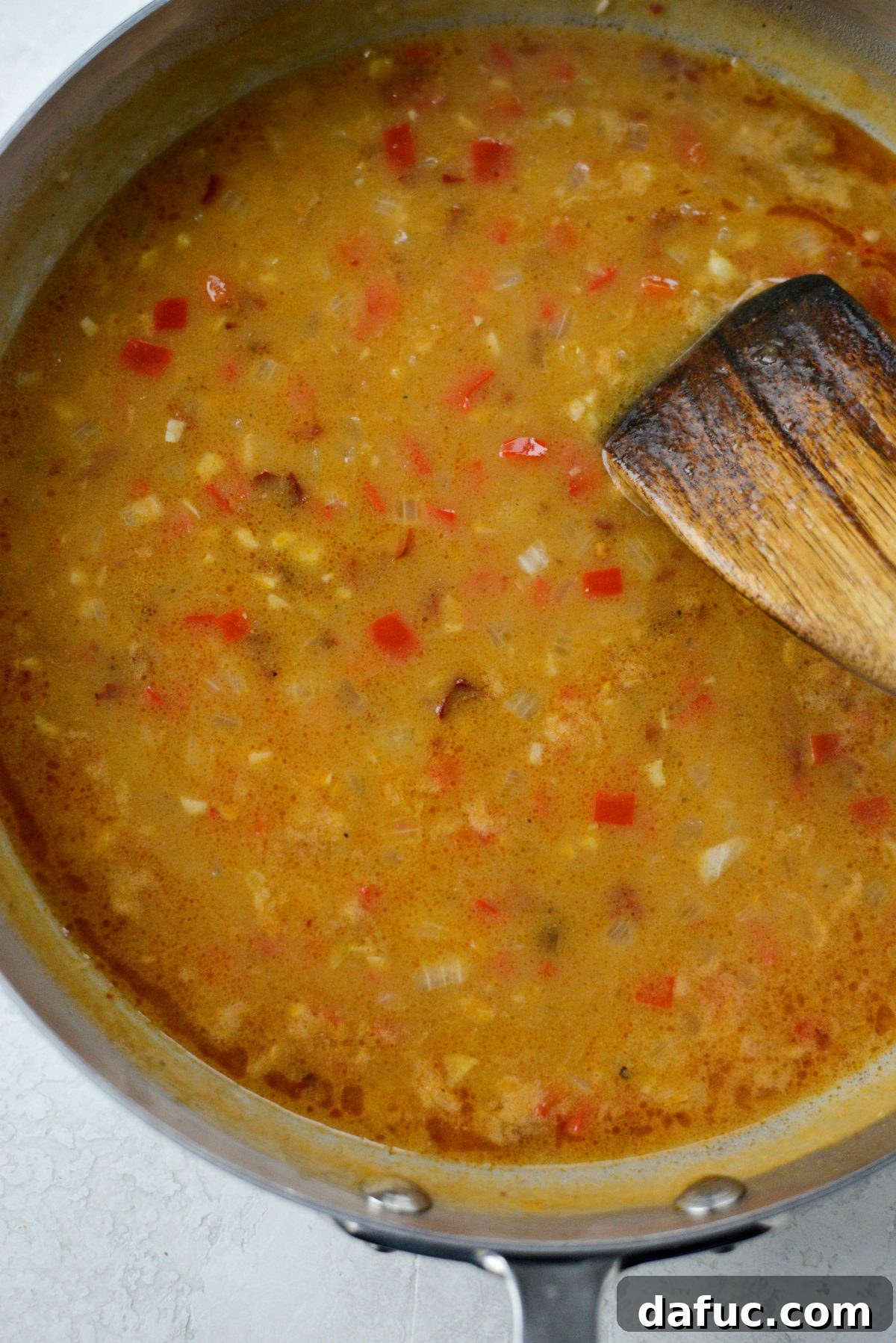 Chicken broth being slowly stirred into the chipotle roux to create the sauce