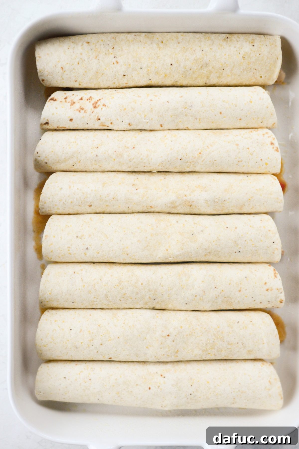 Spoonful of chicken and sauce filling placed on a tortilla for rolling