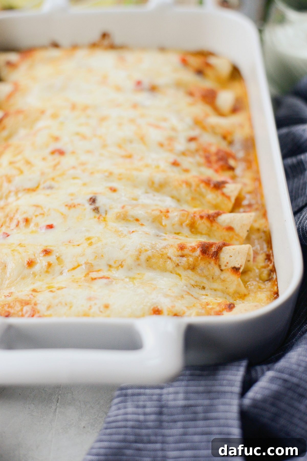 Sprinkling grated Muenster cheese generously over the sauced enchiladas