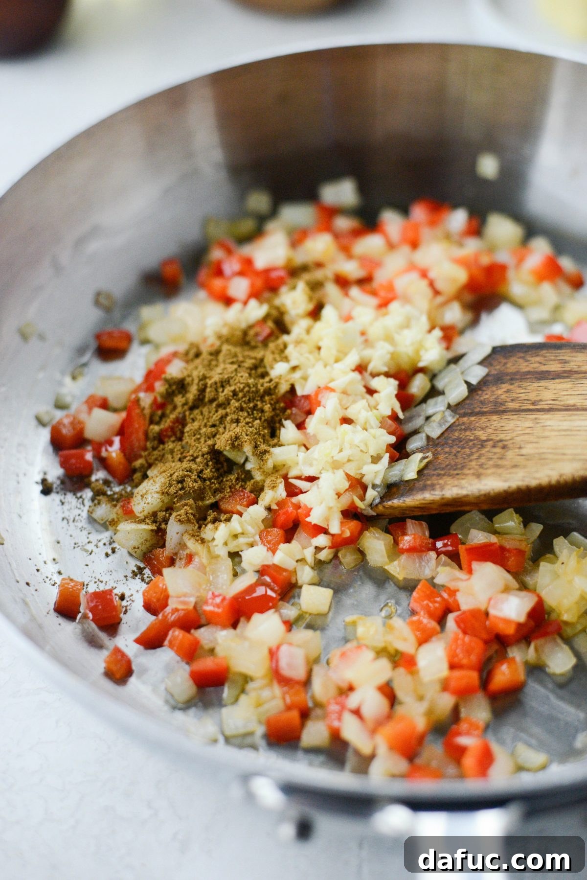Step-by-step image of sautéing onions and bell peppers for enchilada sauce
