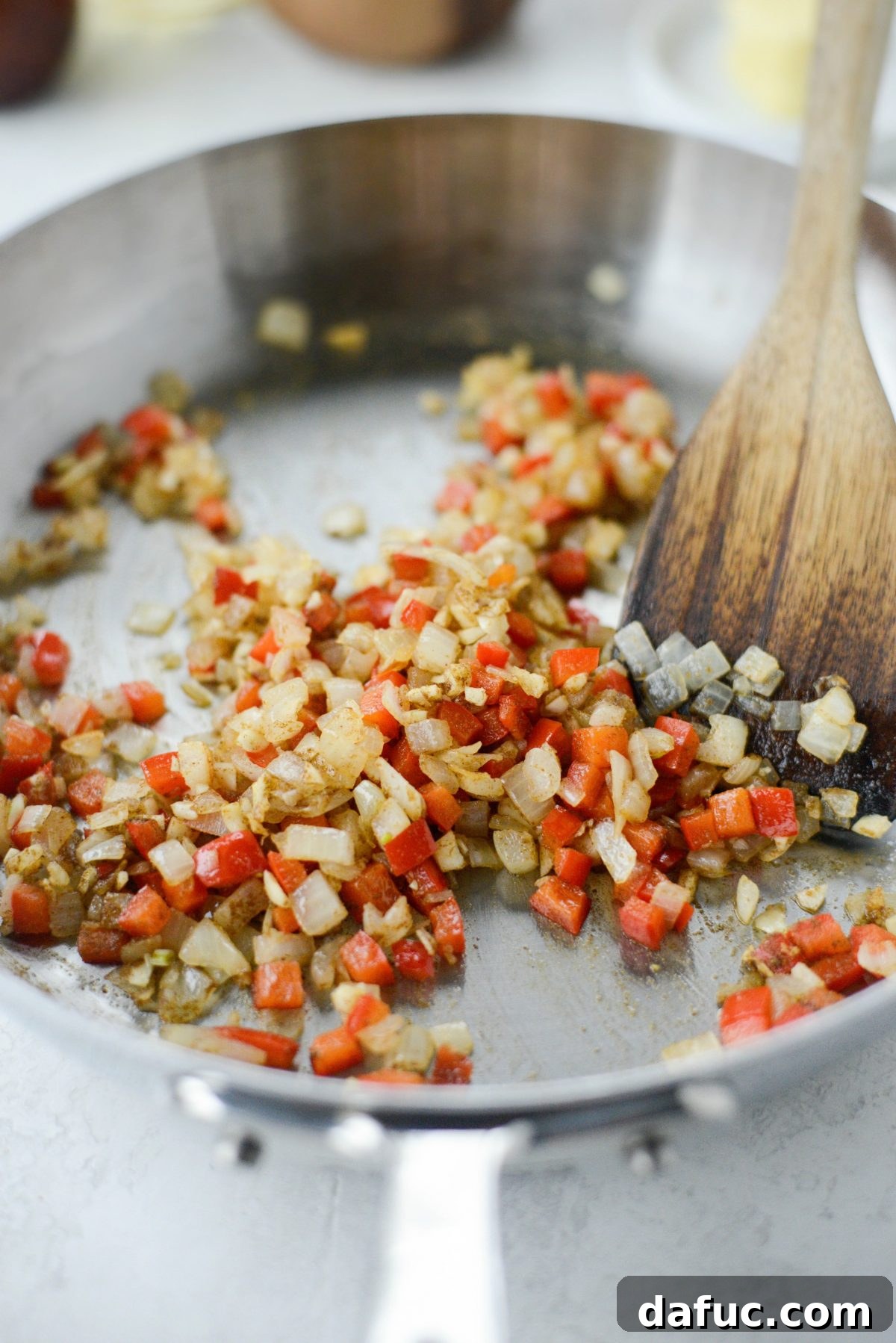 Adding cumin and garlic to sautéed vegetables for chipotle sauce