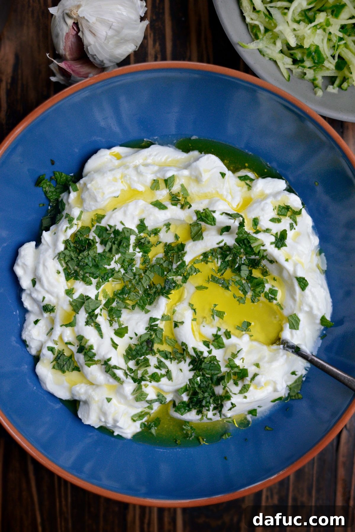 Creamy Homemade Tzatziki 4 Yogurt, olive oil, and mint - A bowl containing creamy Greek yogurt, with fresh mint leaves and olive oil ready to be added.