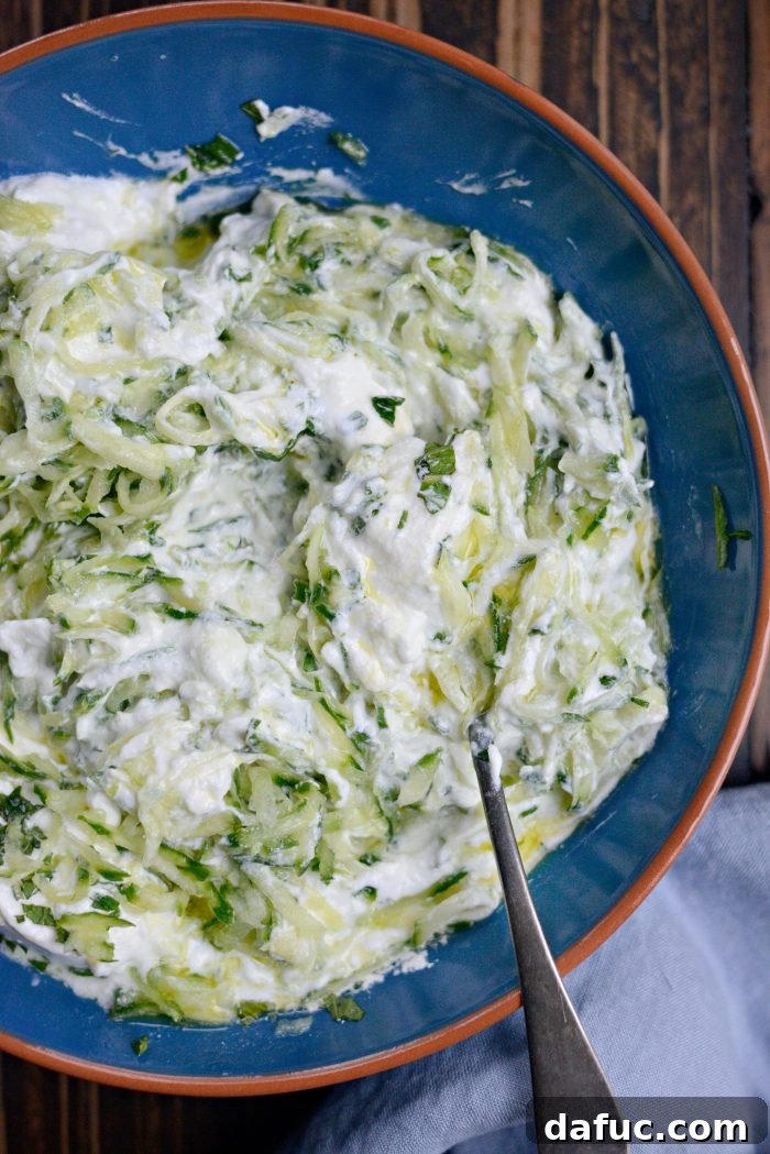 Creamy Homemade Tzatziki 6 Stir to combine - A spoon stirring the ingredients together in a bowl, showing the creamy tzatziki forming.