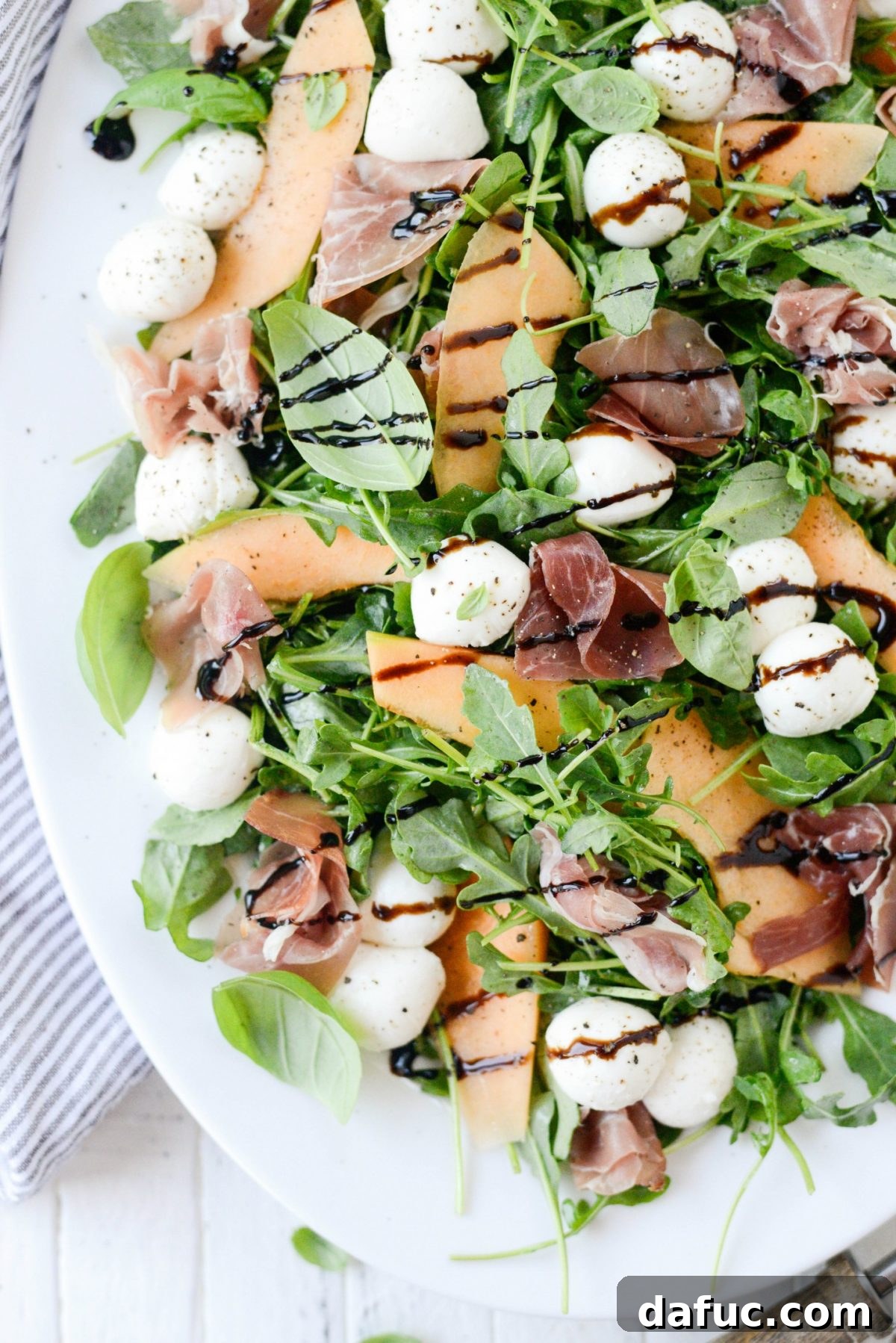 Golden Melon Prosciutto Arugula Fresca 12 Cantaloupe and Prosciutto Arugula Caprese Salad plated, showcasing fresh basil and balsamic glaze