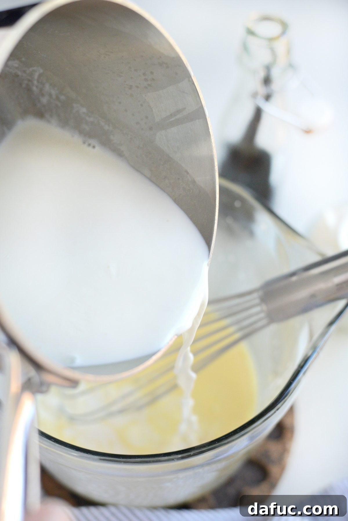 Pouring warm milk into egg mixture