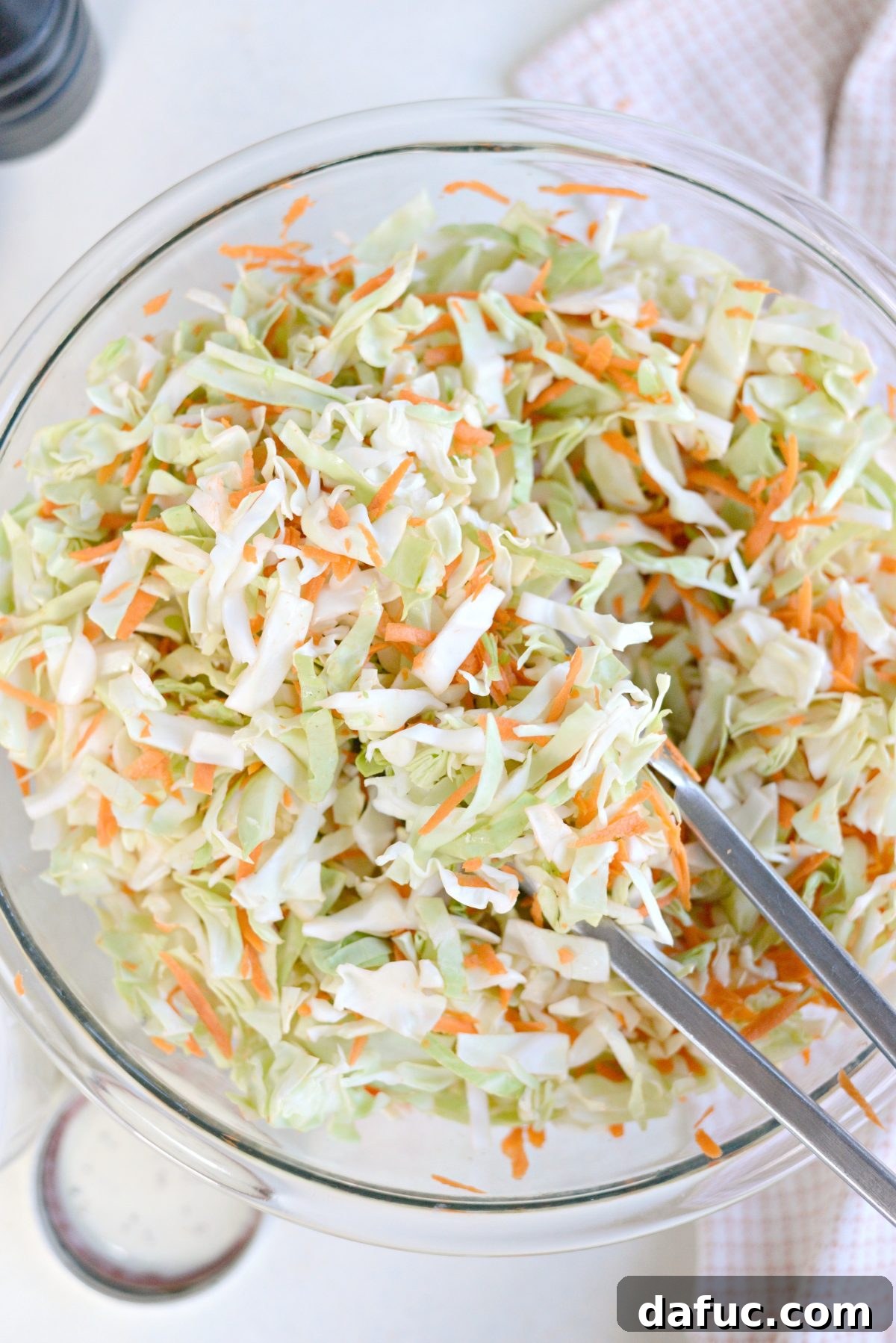 Perfect Classic Coleslaw From Scratch 11 Using tongs to toss shredded cabbage and carrots together in a bowl