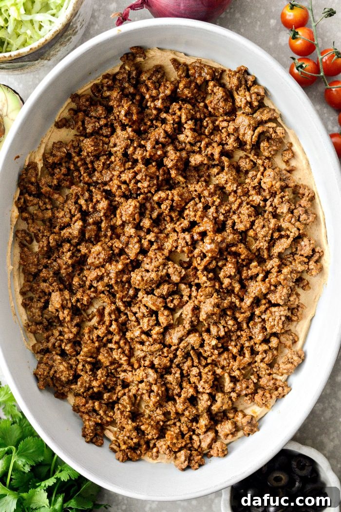 Fiesta Seven Layer Taco Dip 11 Spreading Cream Cheese and Topping with Ground Beef
