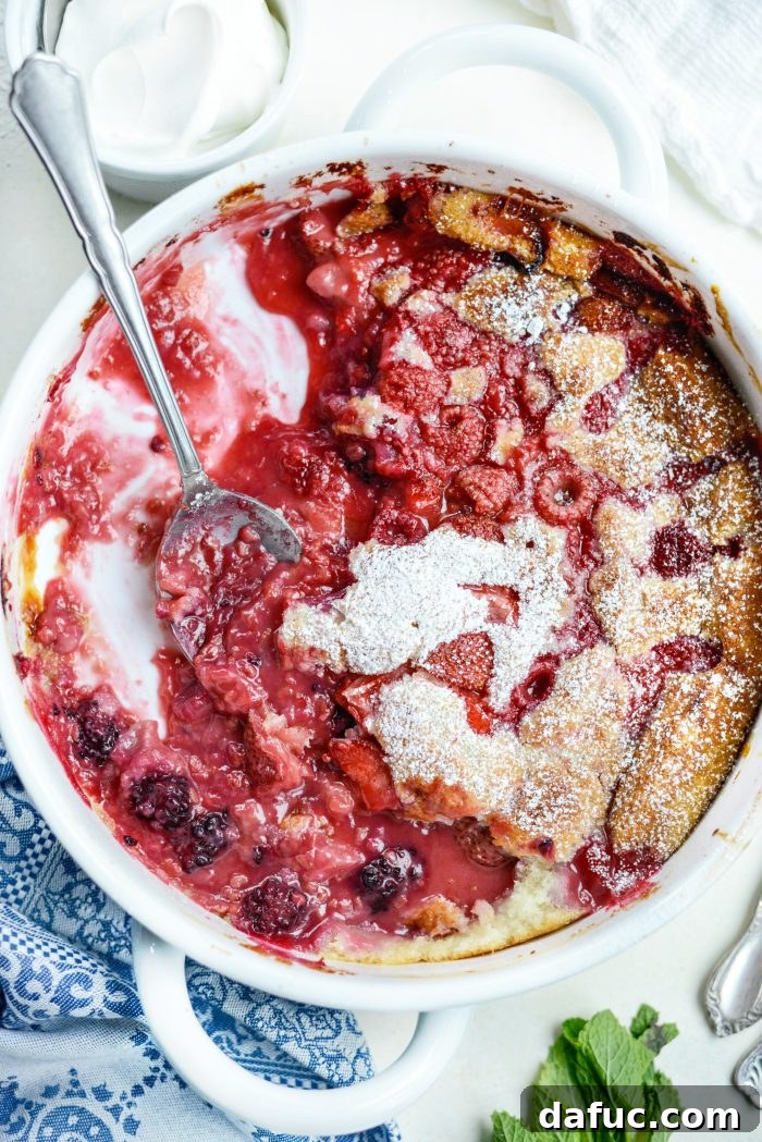 Triple Berry Cobbler with a scoop of vanilla ice cream melting on top, garnished with mint.