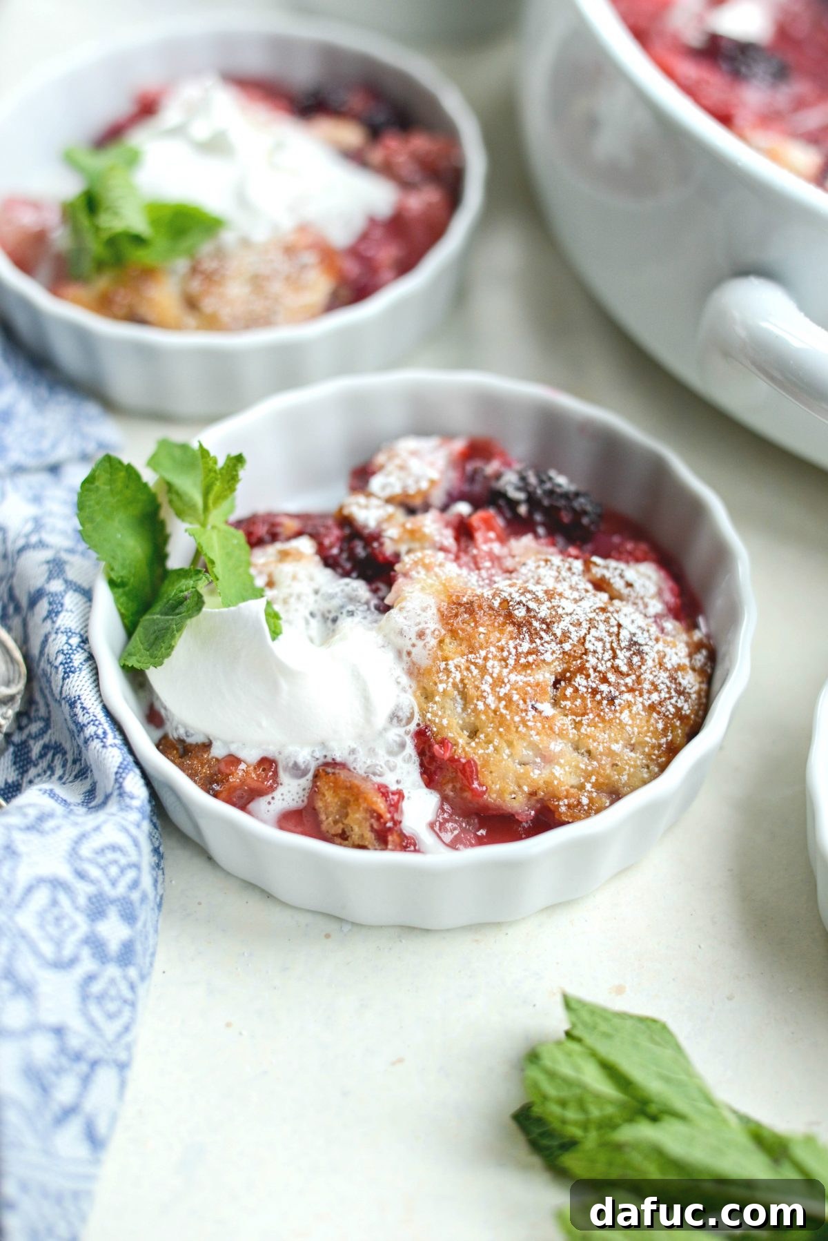 Close-up of a spoonful of Triple Berry Cobbler, showing the fruit and cake-like topping.