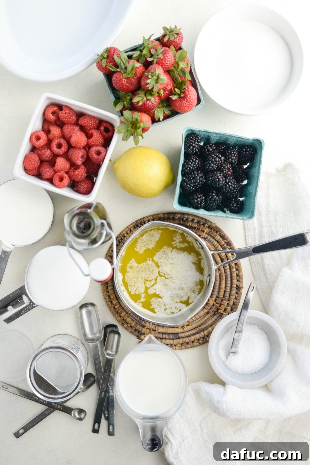 Ingredients for Triple Berry Cobbler laid out on a wooden surface.