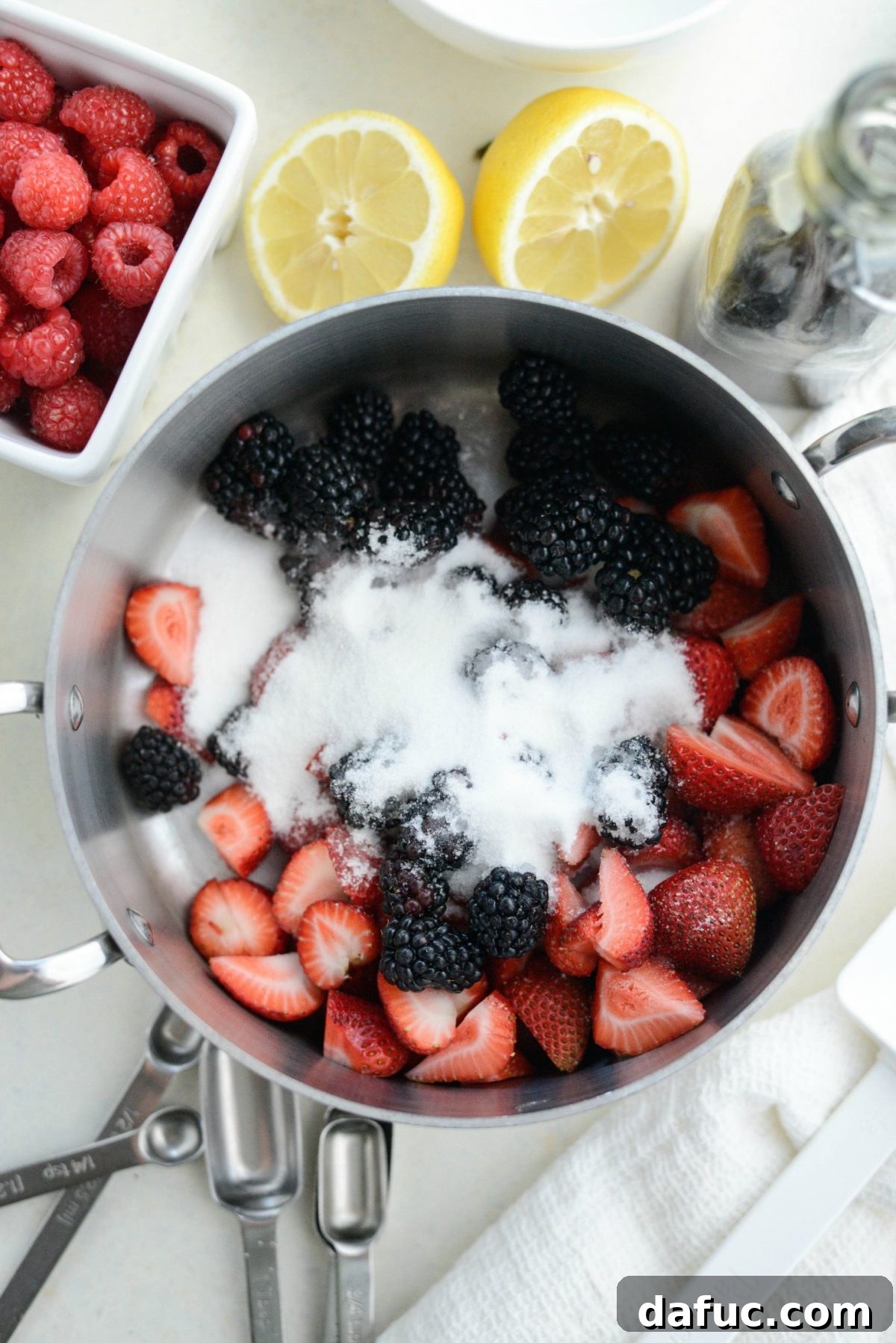 Strawberries, blackberries, sugar, and lemon juice in a saucepan.