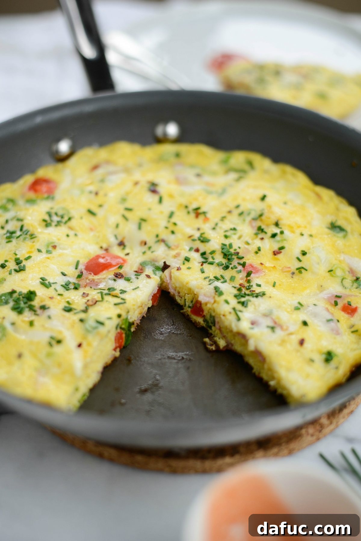 Cowboy Breakfast Frittata 11 Close-up of a Western Frittata wedge on a plate, garnished with chives and red pepper flakes