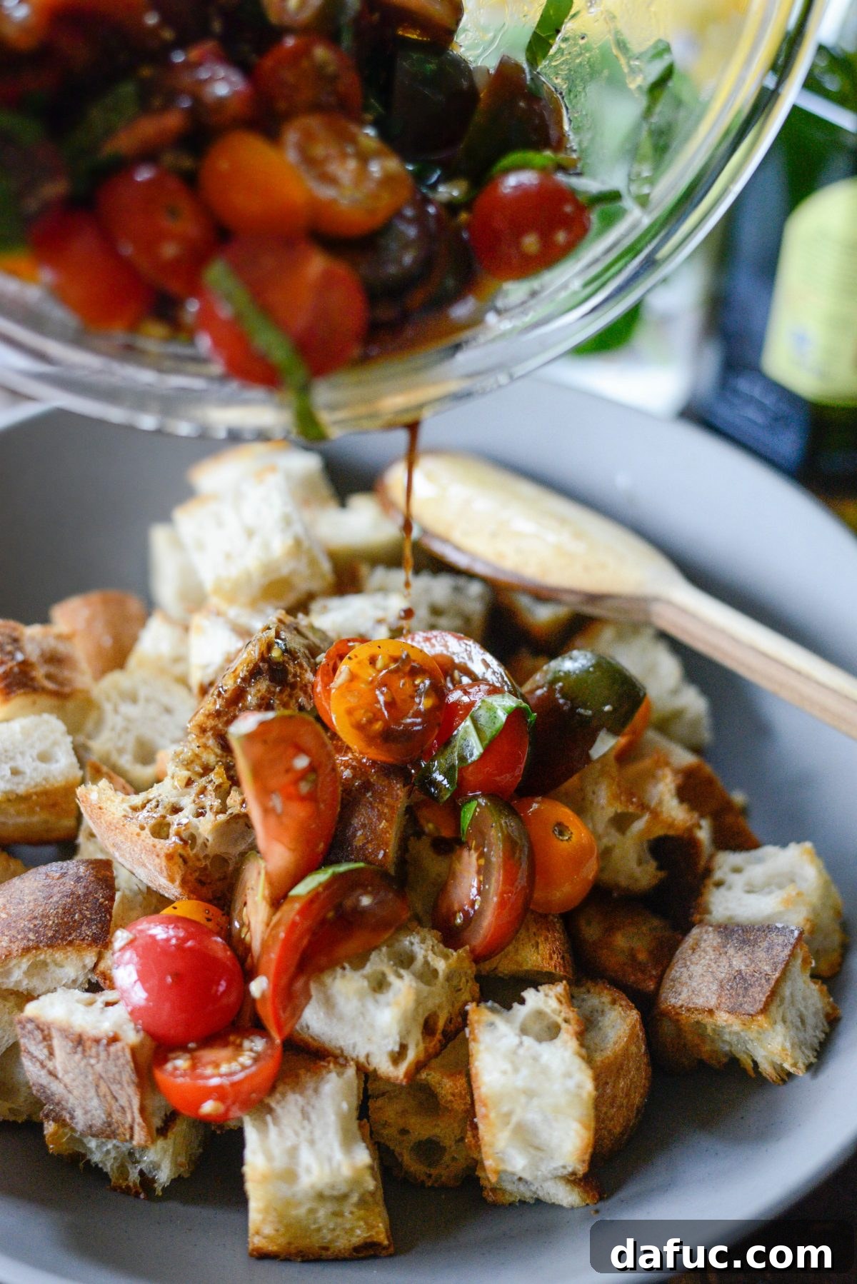 Adding the marinated tomato mixture and all its flavorful liquids over the toasted bread