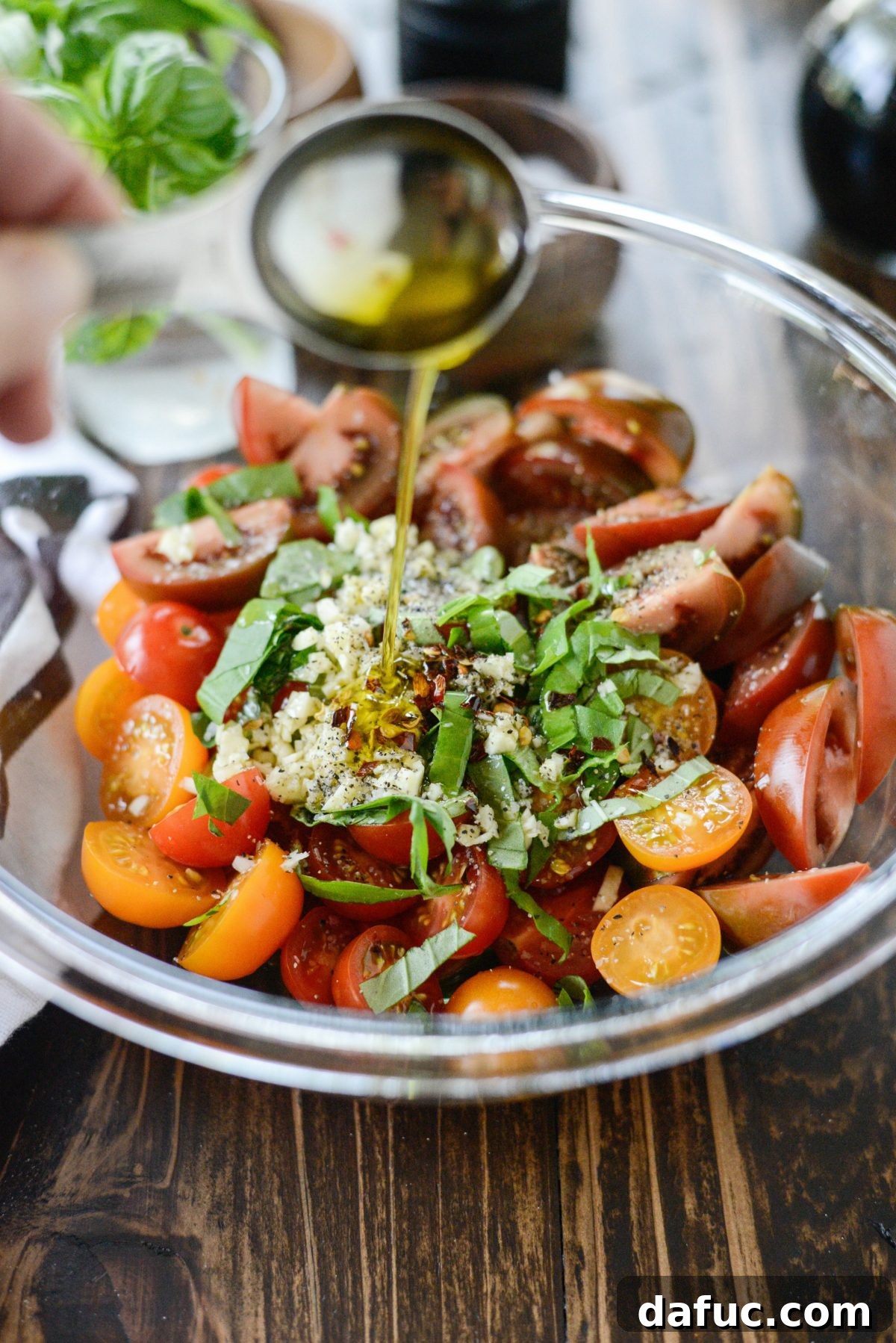 Drizzling high-quality olive oil over the seasoned tomato mixture