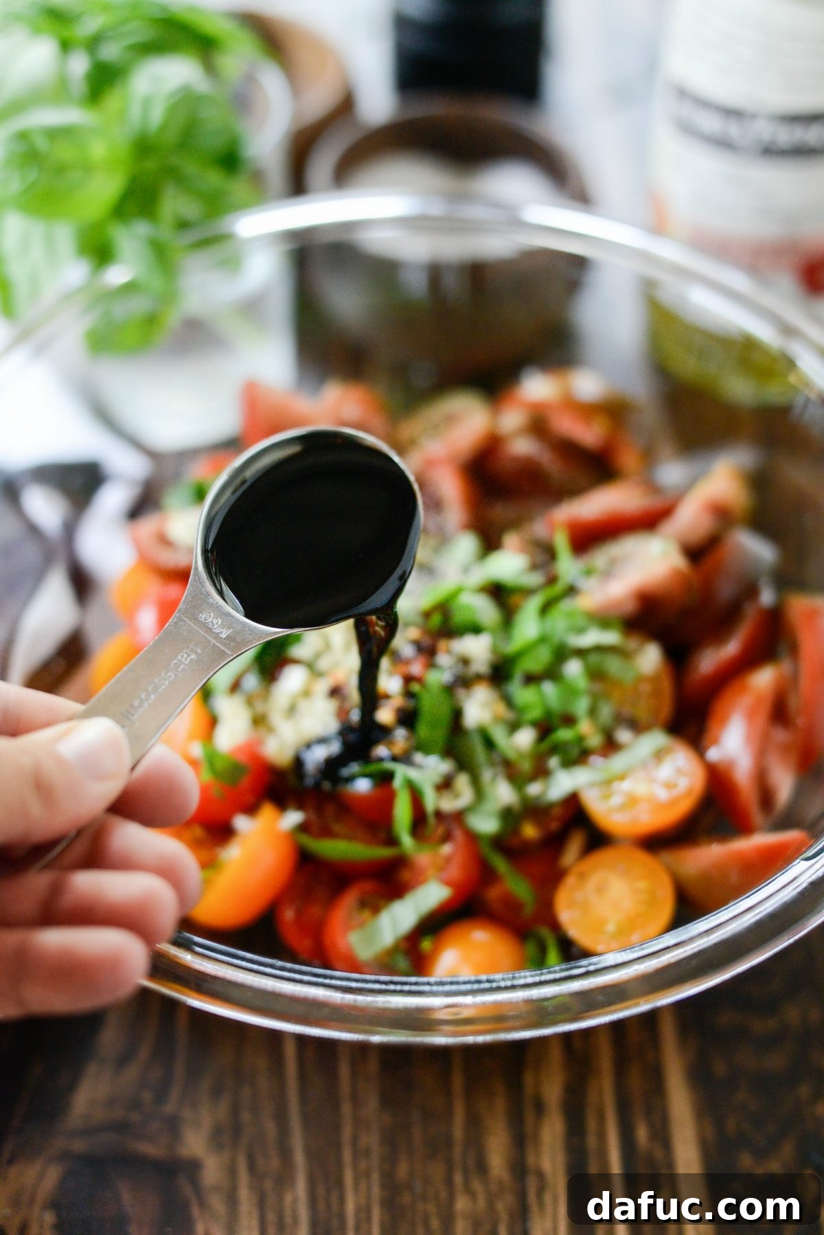 Adding rich balsamic vinegar to the tomato and herb marinade