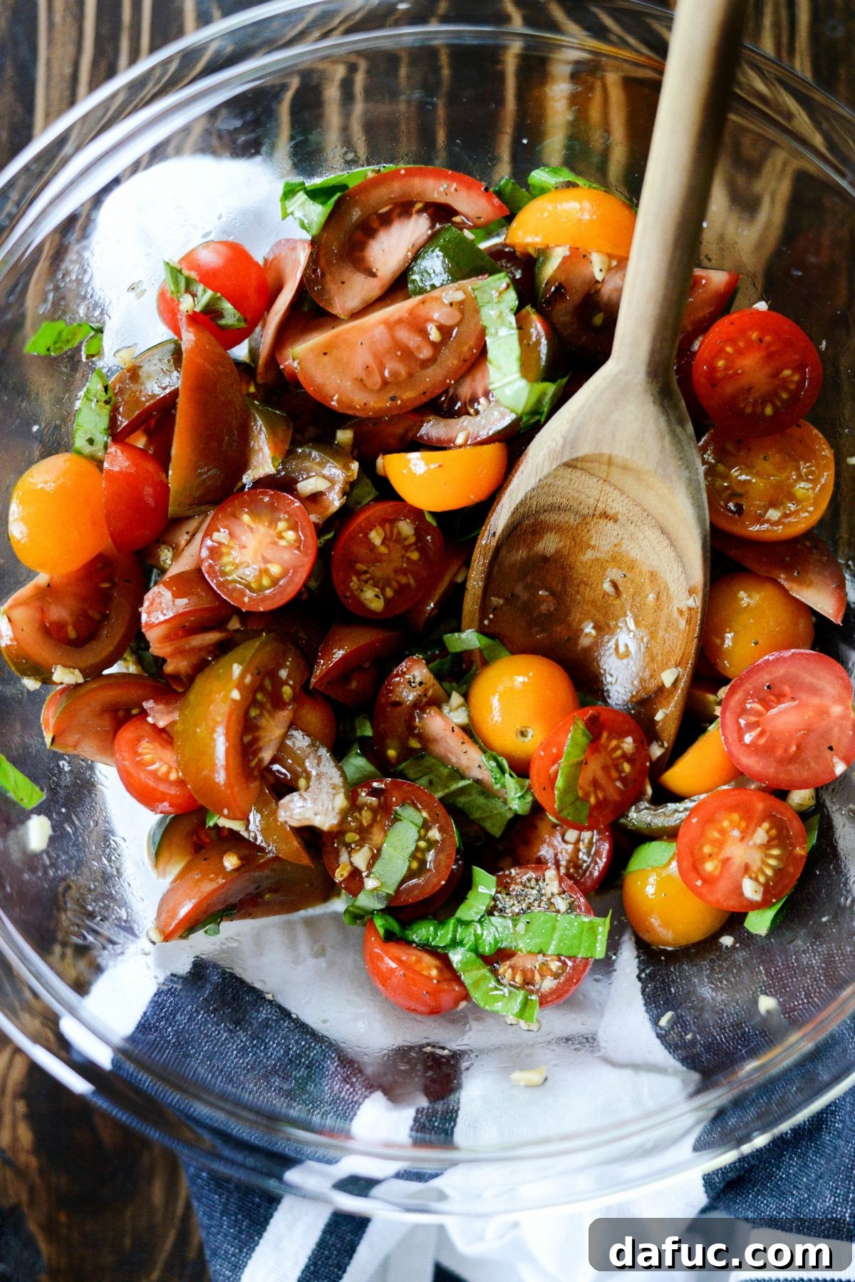 Stirring to combine all the bruschetta ingredients for the tomato mixture, allowing them to marinate