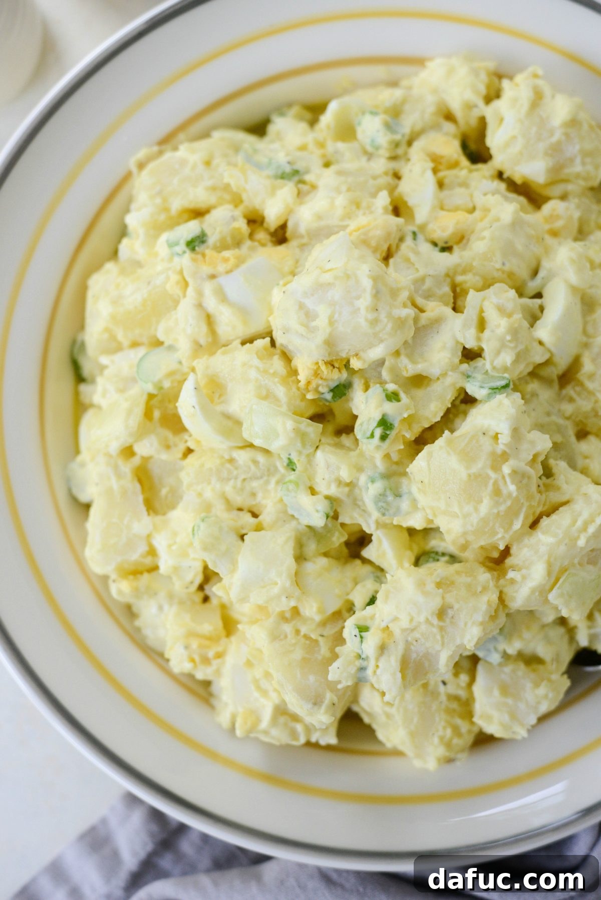 A large serving bowl of Aunt Penny's Classic Potato Salad, garnished and ready to be enjoyed at a festive gathering.