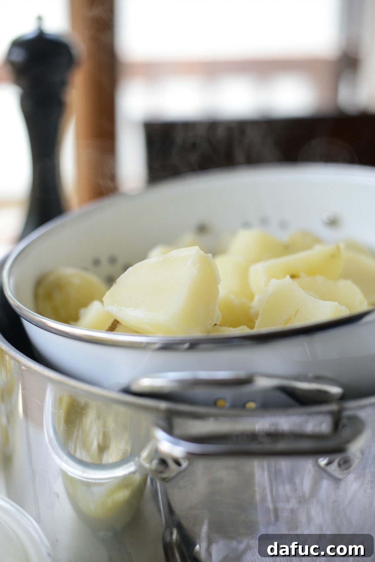 Cooked potatoes being drained in a colander.