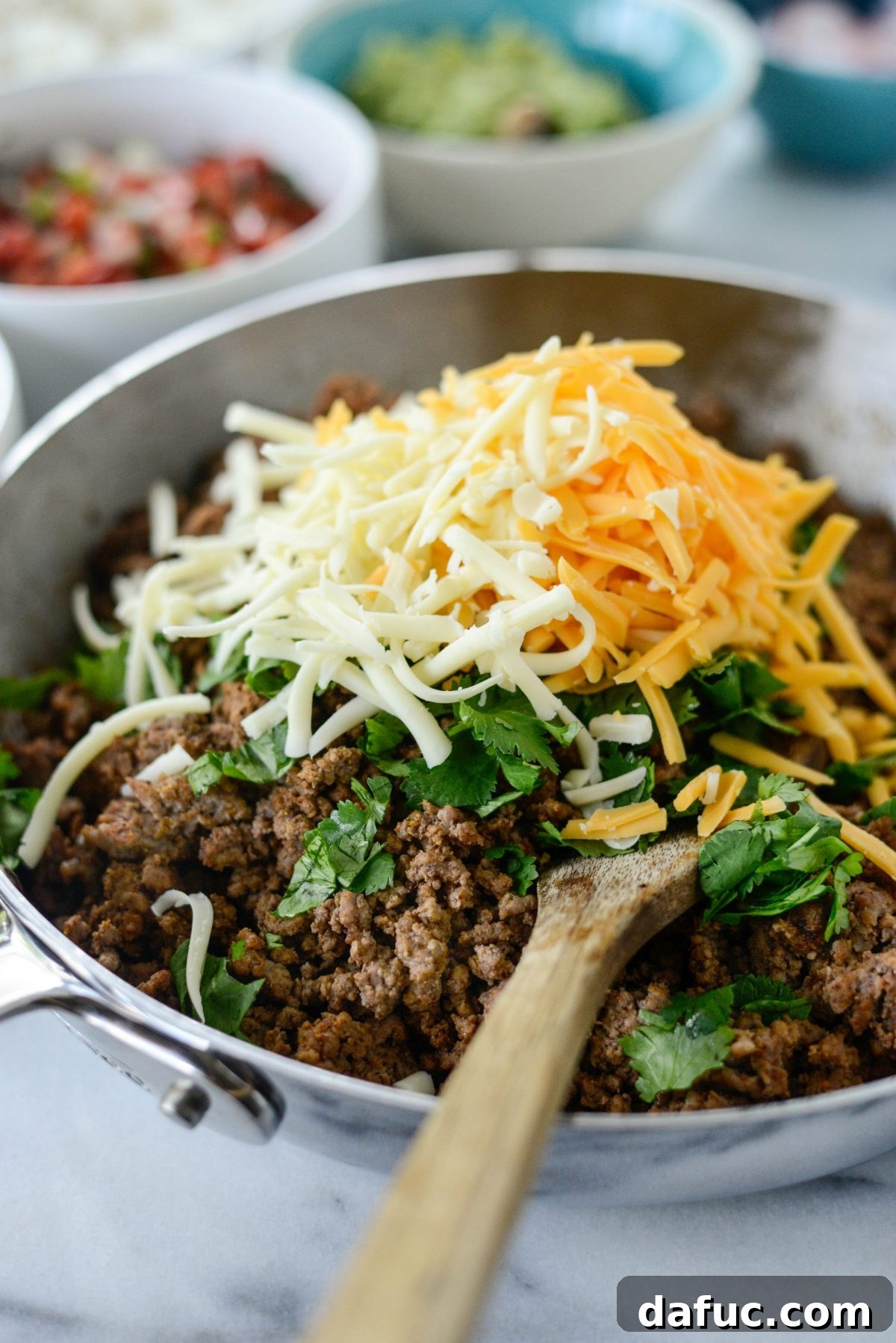 Beefy Bean Burrito Bowls 5 Adding shredded cheese to the seasoned beef mixture