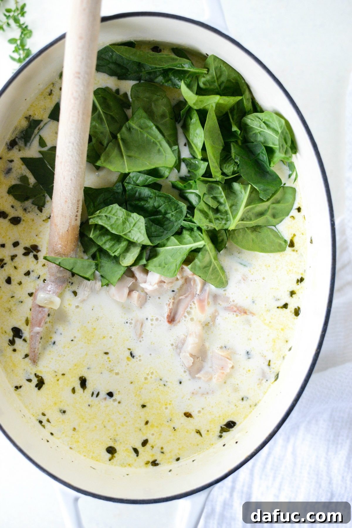 Adding cooked gnocchi, spinach, and shredded chicken to the soup