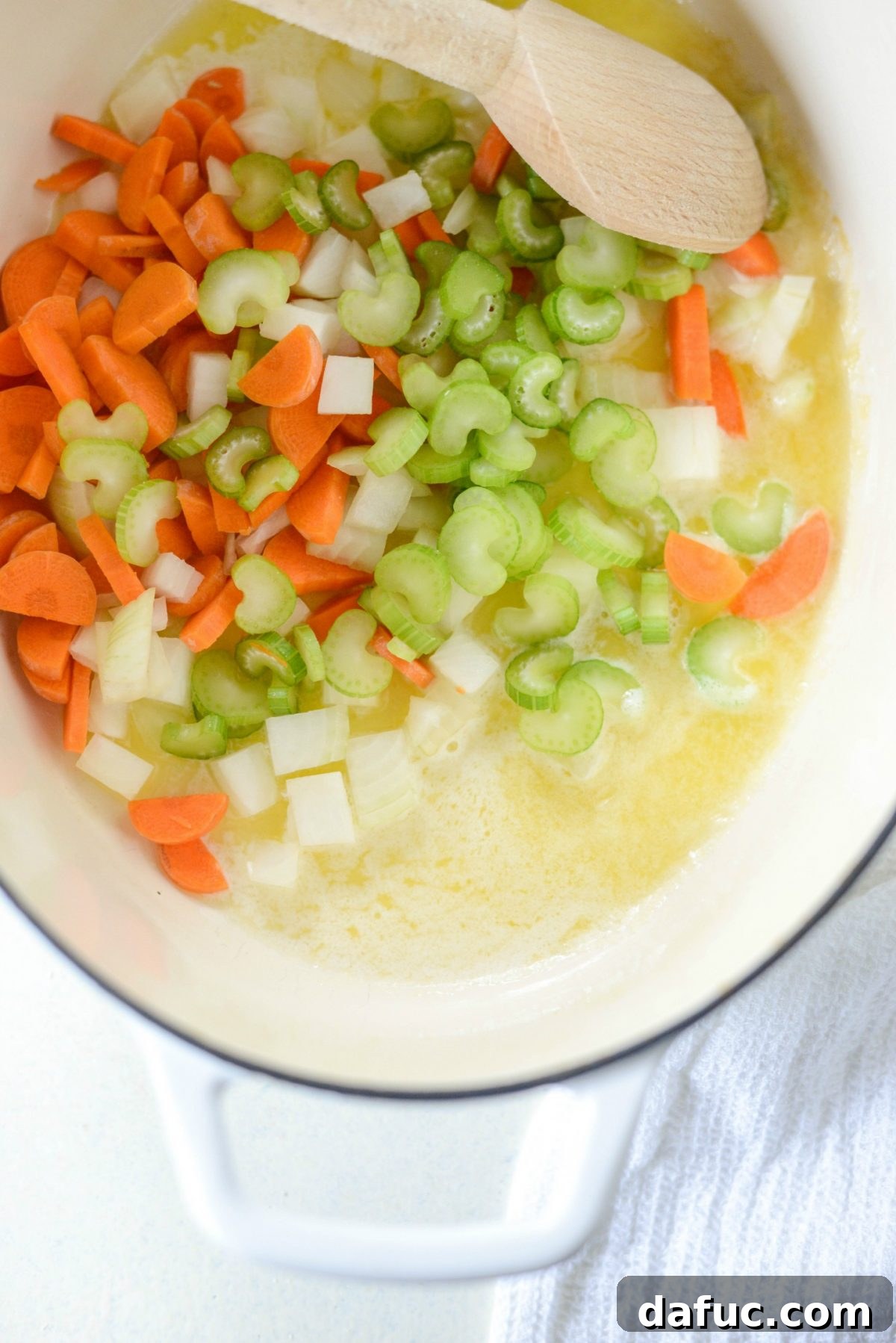 Adding diced carrots, onions, and celery to the pot