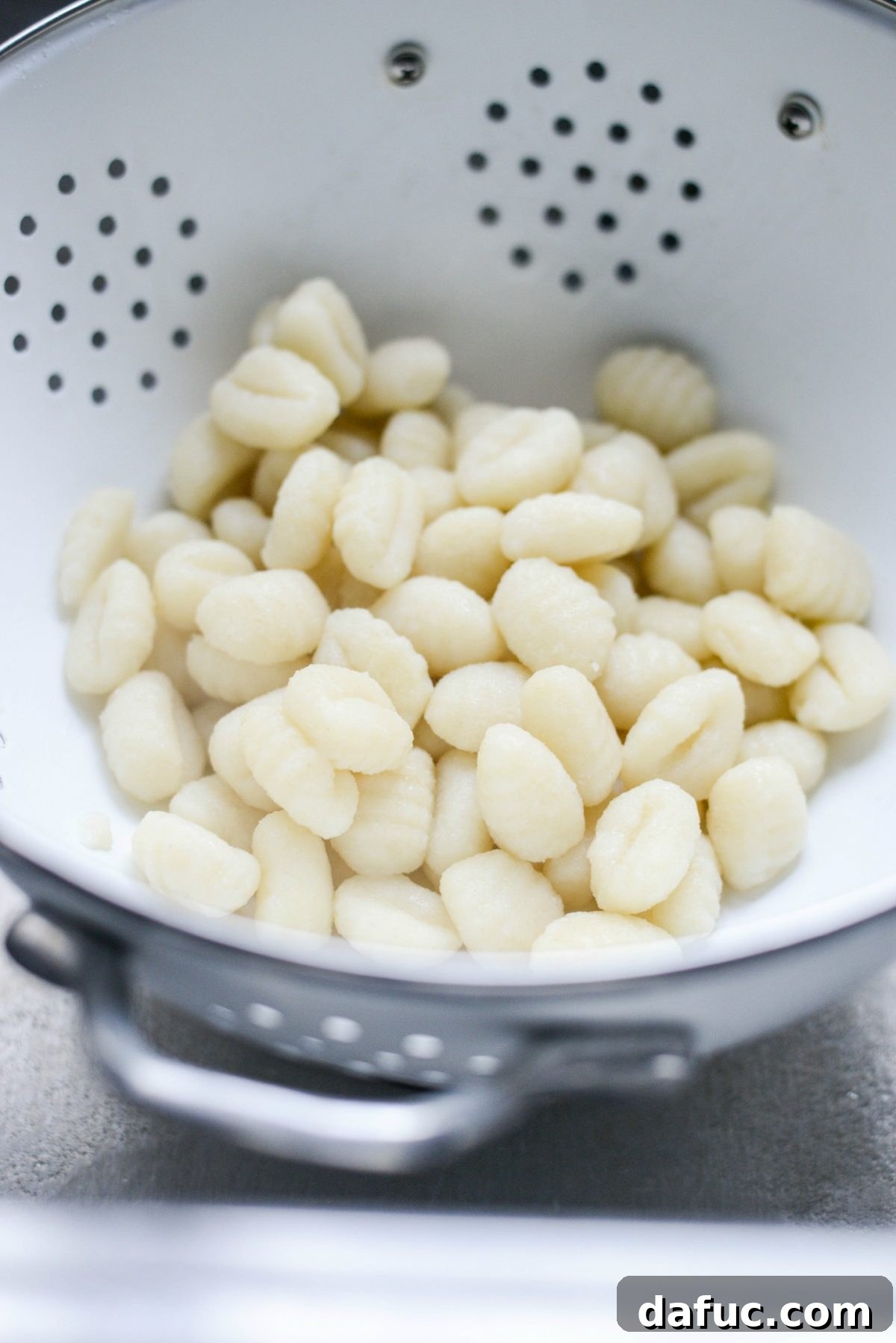 Draining cooked gnocchi into a colander