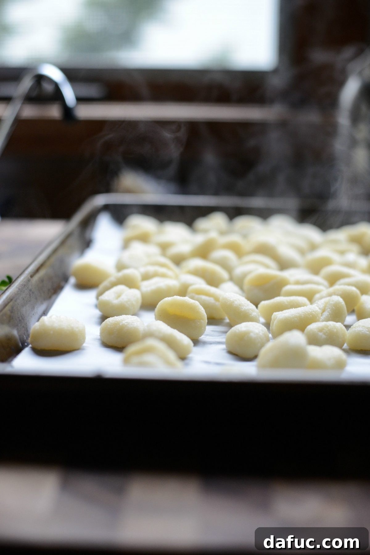 Spreading cooked gnocchi on parchment paper to prevent sticking