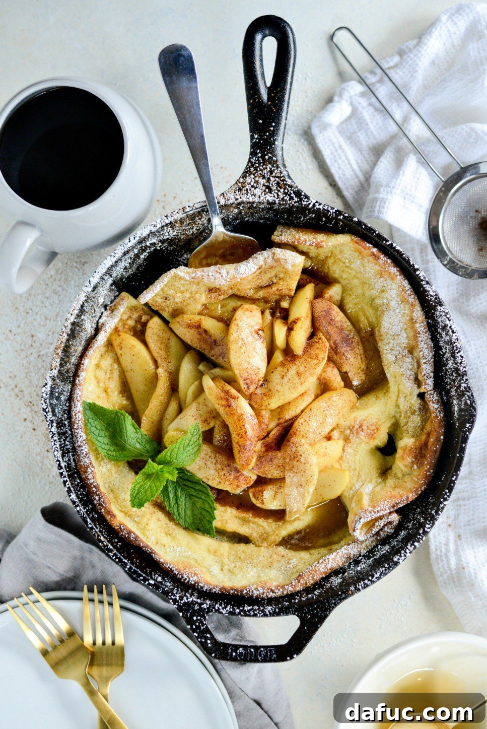 Sweet Caramel Apple Skillet Puff 14 An aerial shot of the finished Caramelized Apple Dutch Baby with serving utensils.