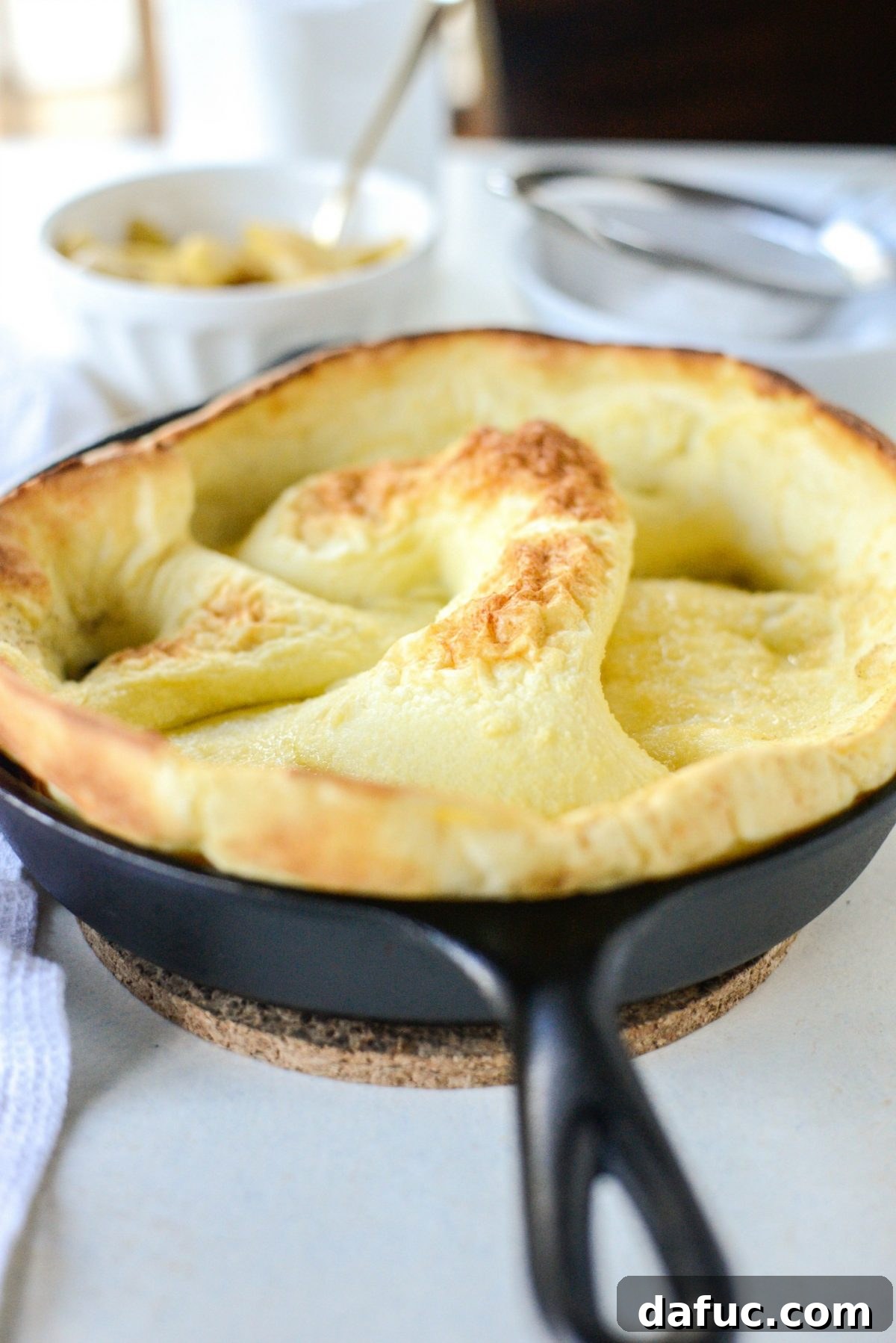 Sweet Caramel Apple Skillet Puff 10 Fluffy golden Dutch Baby pancake just out of the oven in a cast iron skillet.