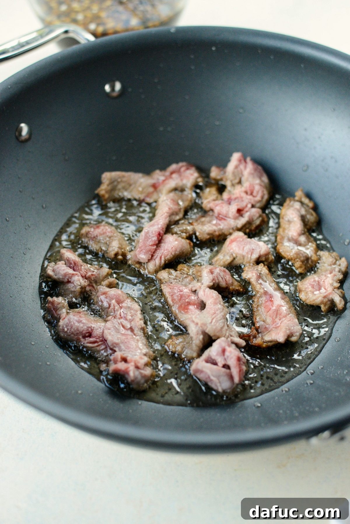 Speedy Sesame Mongolian Beef 8 Cooking thinly sliced beef in oil in a large wok
